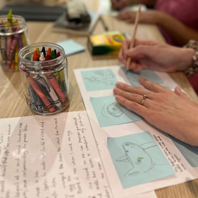 A person writes on a sticky note laid out to show a comic strip.