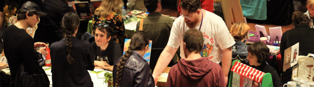 Customers purchasing comics from exhibitors at the Perth Comic Arts Festival market hall.